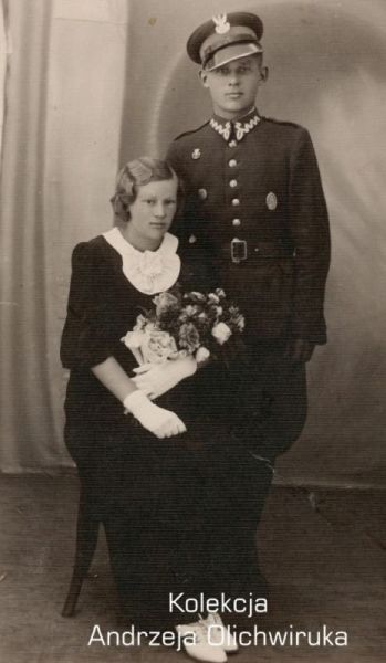 Żołnierz KOP znajduje się prawej strony. Obok niego siedzi kobieta, trzymająca w dłoni bukiet kwiatów. Zdjęcie pozowane.