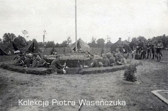 Żołnierze KOP oraz harcerze w czasie posiłku na terenie obozu polowego.
