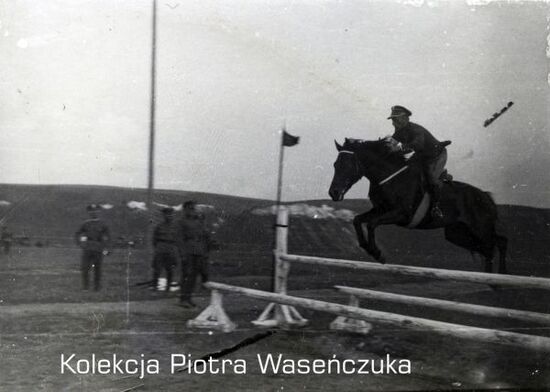 Żołnierz KOP na koniu skacze przez płotki.