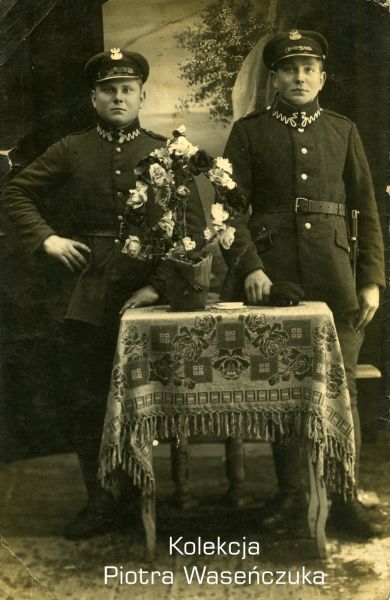 Dwóch żołnierzy KOP pozujących przy stoliku z kwiatami