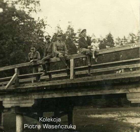 Trzech żołnierzy KOP na moście, na pierwszym planie mężczyzna w cywilu z dzieckiem