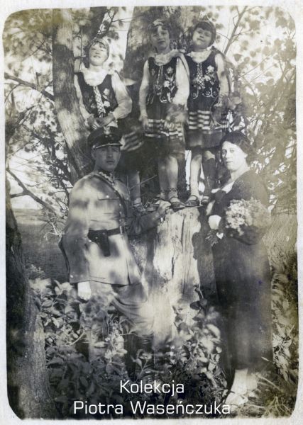 Żołnierz KOP z rodziną- żoną z bukietem kwiatów i trzema dziewczynkami w ludowych strojach