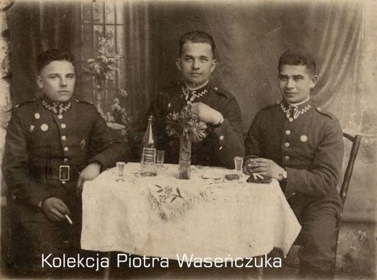 Trzech żołnierzy KOP w czasie biesiady przy stole.