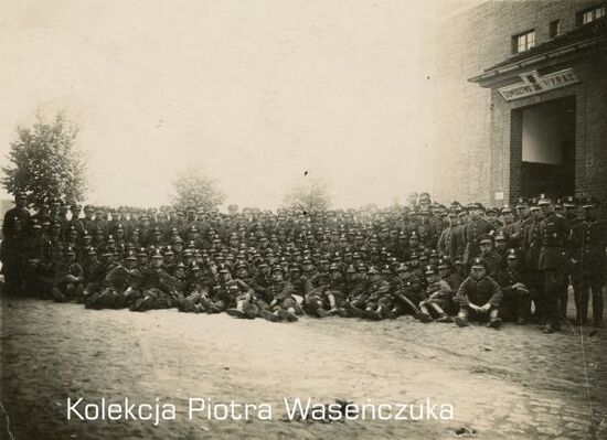 Zdjęcie pozowane dużej grupy żołnierzy KOP na tle budynku Dowództwa 7 Pułku Artylerii Ciężkiej.
